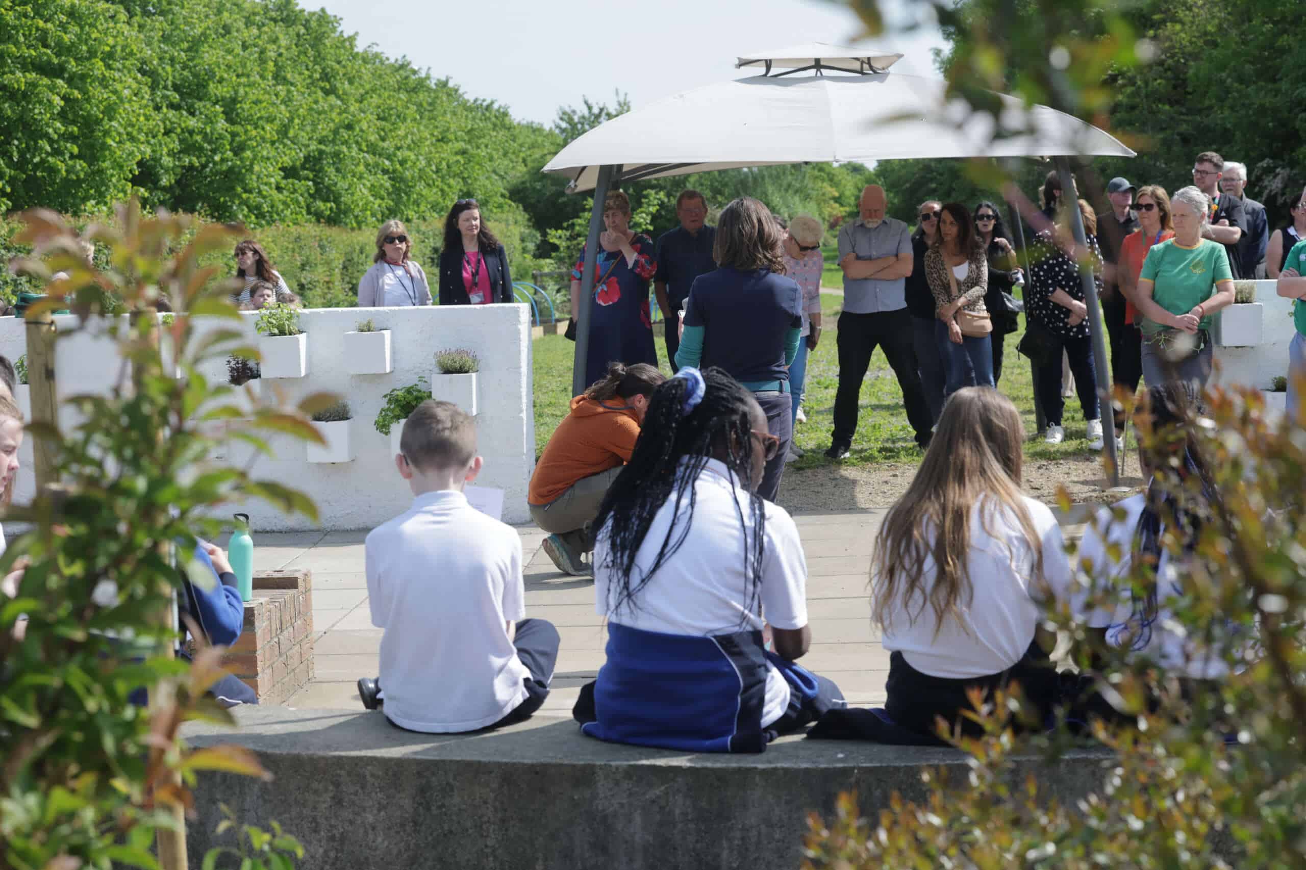 children listening to a speech in the community garden