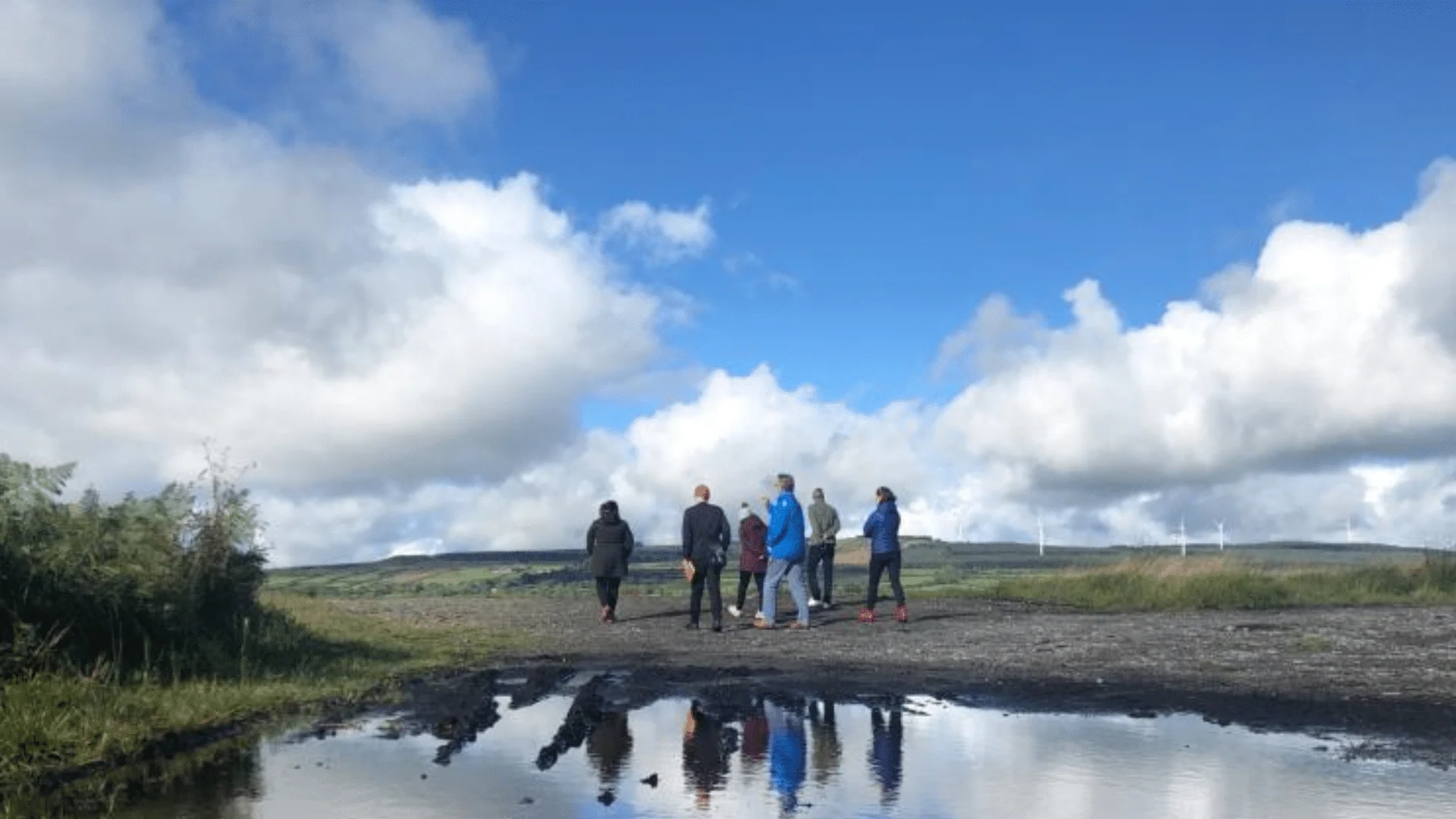 People walking on a bog, with their reflections in a puddle